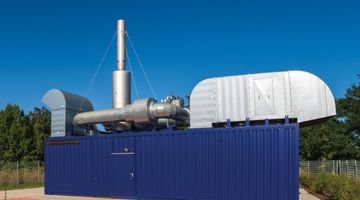 Ein blauer Container mit einem Aufbau aus Rohren und Schornsteinen