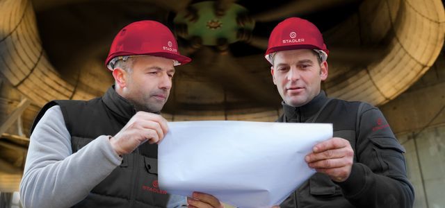 Zwei Männer besprechen eine Technische Zeichnung vor einer Turbine