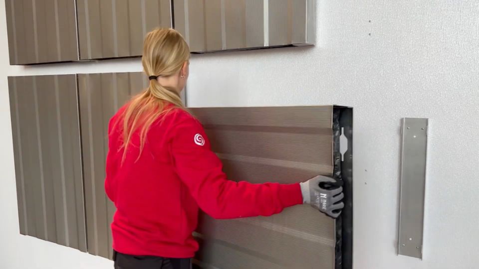 Person hängt ein ESSONIC Gerät aus Metall an eine Wandhalterung.