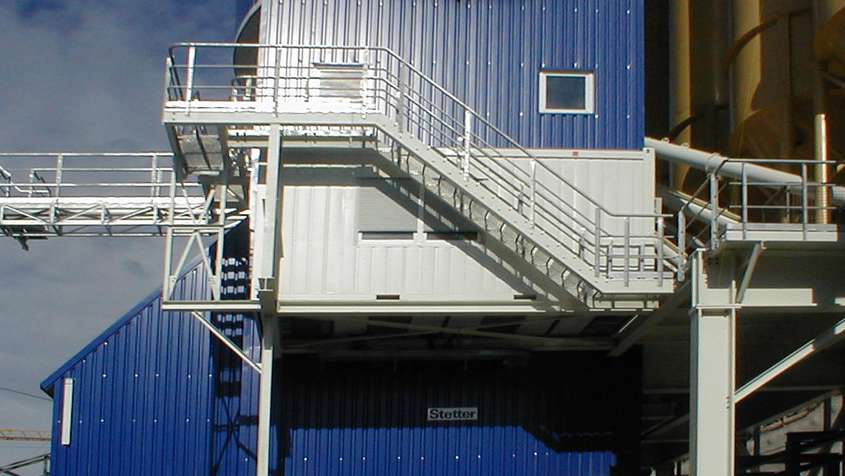 Trapezblechfassade für Mischanlage am Lötschbergtunnel Ausschnitt eines Gebäudes mit blauer Trapezblechfassade und einer weißen Treppe an der Außenseite