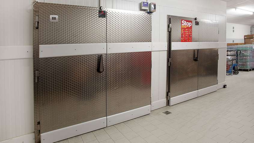 DREHTÜREN 2 - FLÜGELIG MIT RAMMSCHUTZSYSTEM Zwei Kühlraumtüren aus Metall mit einem Hexagon-Muster