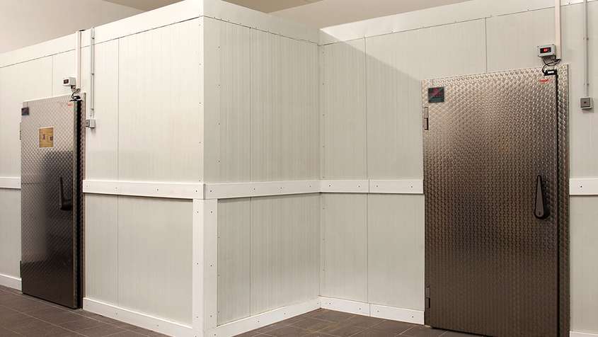 KÜHLRAUM MIT ZUGANGSTÜREN Weiße Wand mit zwei Türen an der rechten und linken Bildseite