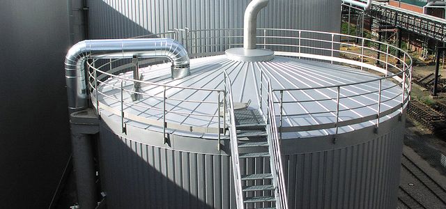 Ein großes Silo mit einer Treppe aus Metall. Etwas Dampf ströhmt aus einem Rohr an der Spitze des Silos