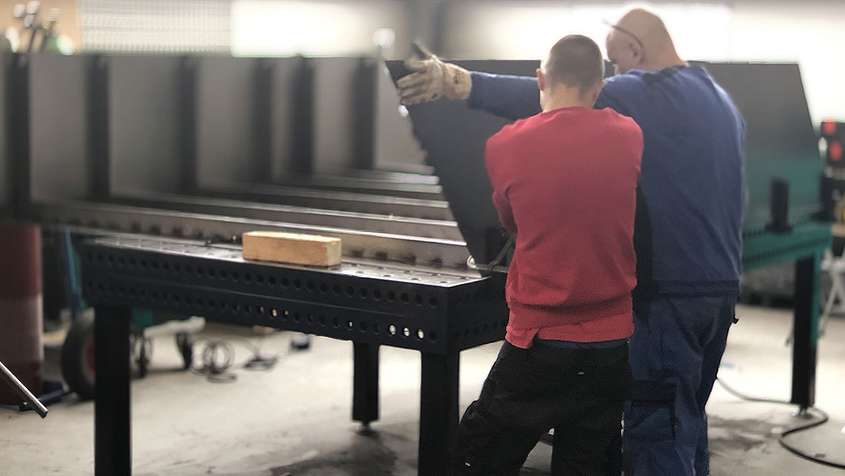 Sheet metal construction Two men working on a piece of sheet metal together