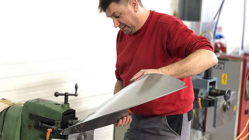 Sheet metal working beading A man beading a piece of sheet metal