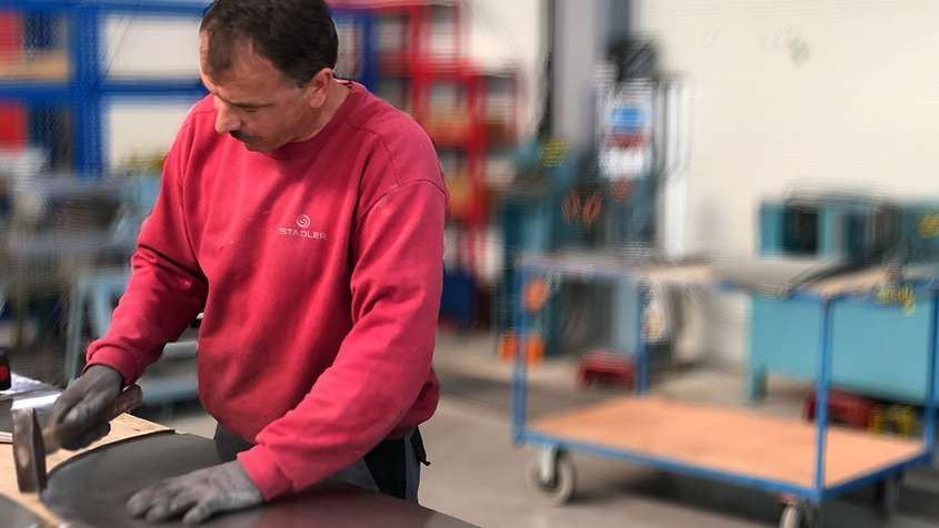 Sheet metal working flanging A man flanging a piece of sheet metal