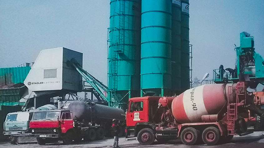MOBILE MISCHANLAGENVERKLEIDUNG RUSSLAND Rote Betonmischer vor einem türkisen Silo-Komplex