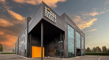 Perspective view of a modern industrial building in front of a sunset. 